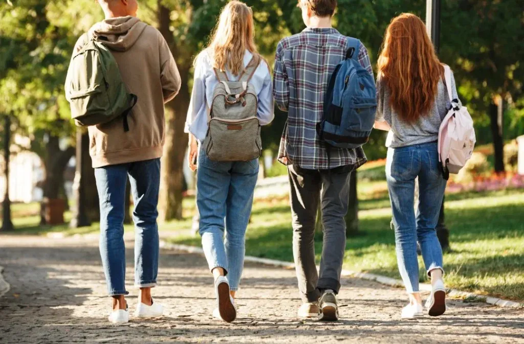 Jeunes avec sacs à dos marchant en groupe sur un chemin extérieur — sorties, déplacements et vie scolaire hors des murs — RC scolaire RMA Tanger